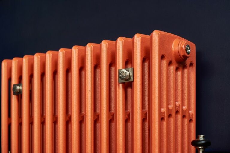 Lifestyle image of orange Castrads Grace 6 Column cast iron radiator.