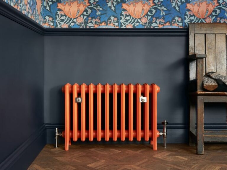 Llifestyle image of an orange Grace cast iron radiator with Hydronic Windsor valves